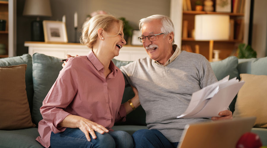 Elderly Couple Smiling, Insurance Paperwork in Hand